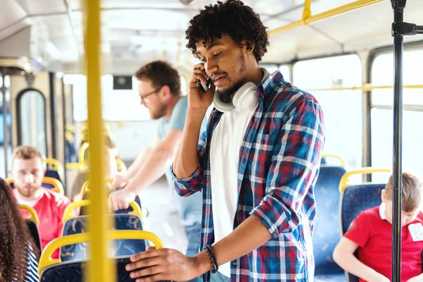 市バスに乗っている間呼び出しのスマート フォンを使用して若いアフリカ系アメリカ人の男 背景の通勤に — ストック写真