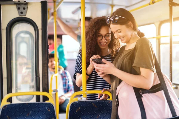 两个美丽的年轻女子在公交车上谈论智能手机 — 图库照片