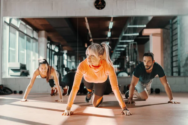 一群有健康习惯的运动型人在健身房的地板上做力量练习 在背景镜像中 — 图库照片