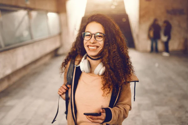 Dişlek Gülümseme Metroda Ayakta Akıllı Telefon Kullanarak Uzun Kıvırcık Saç — Stok fotoğraf