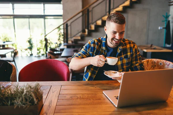 Freelancer Com Sorriso Rosto Bebendo Café Olhando Para Laptop Enquanto — Fotografia de Stock