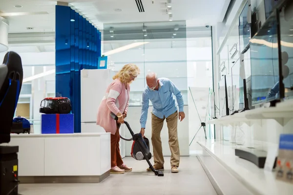Pasangan Senior Yang Bahagia Mencoba Vacuum Cleaner Baru Interior Toko — Stok Foto