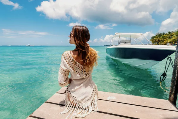海や晴れた日を楽しむ夏のドレスの桟橋の上に座って長い髪の白人ブルネットの形をきれいに 左側にあるヨットの幹部で — ストック写真