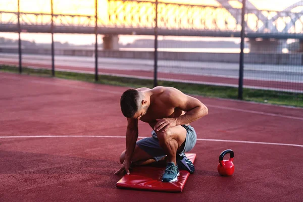 Shirtless Muscular Homem Ajoelhado Posando Quadra Pela Manhã — Fotografia de Stock