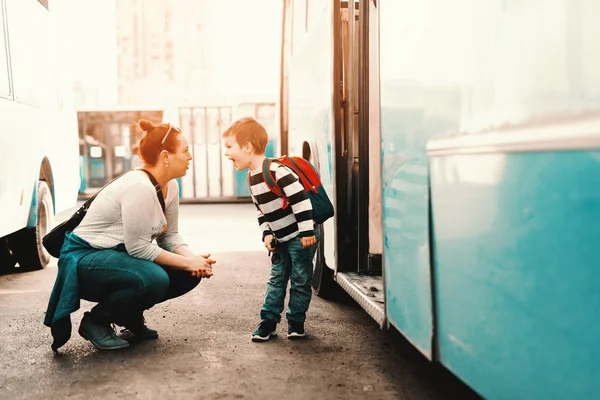 母はバスの前にしゃがんだ彼女の息子と話していると言っています 子供が学校に行く — ストック写真
