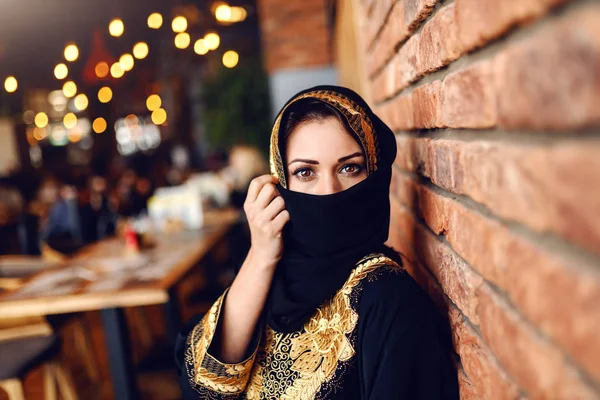 美丽的穆斯林妇女在传统的服装覆盖她的脸与围巾 而坐在自助餐厅 — 图库照片