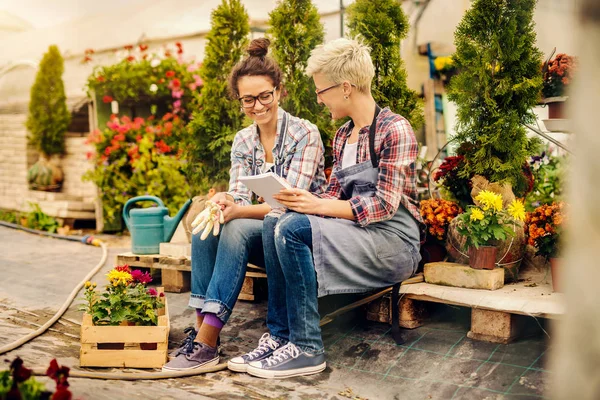 Deux Belles Fleuristes Féminines Assises Extérieur Faisant Liste Des Fleurs — Photo