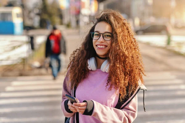 Dişlek Gülümseme Kulaklık Sokakta Akıllı Telefon Kullanarak Boynuna Güzel Genç — Stok fotoğraf