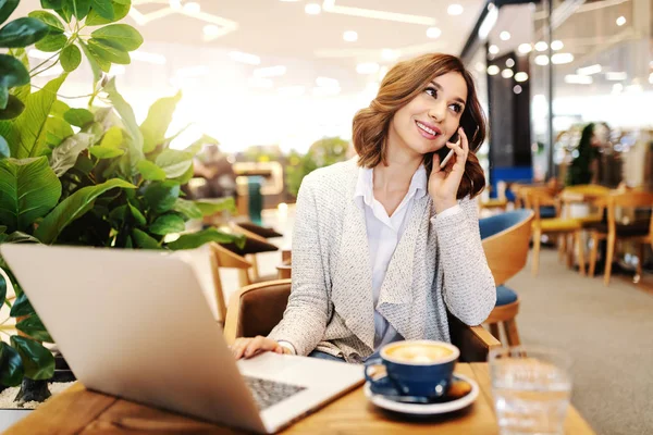 Gülümseyen Kadını Çekici Kafeteryada Otururken Akıllı Telefon Dizüstü Kullanarak Rahat — Stok fotoğraf