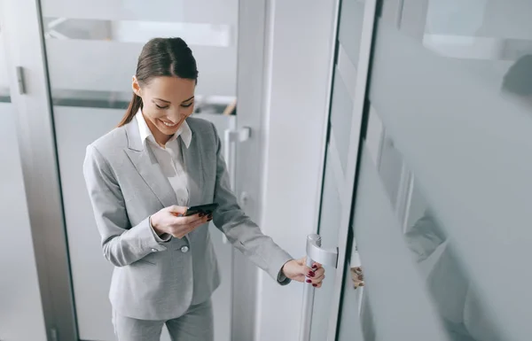 Atraktivní Brunetka Kavkazský Formální Oblečení Pomocí Chytrého Telefonu Zadání Úřadu — Stock fotografie