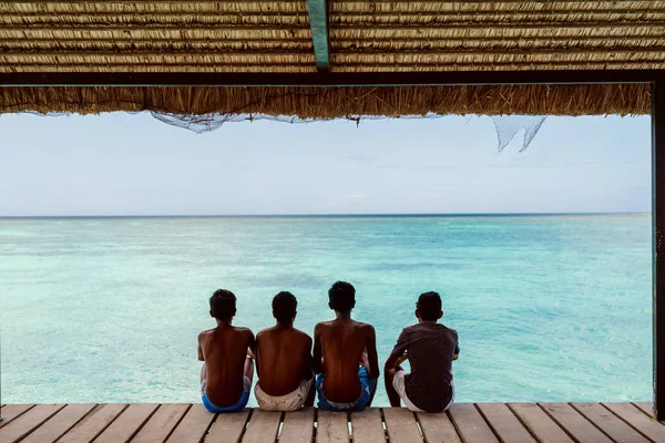 Quattro Ragazzi Abbronzati Seduti Sul Molo Guardare Bellissimo Oceano Blu — Foto Stock