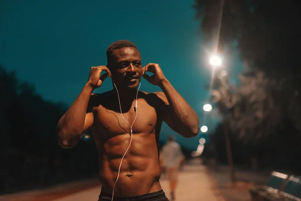 Afrika Gömleksiz Erkek Koşucu Gece Yarış Pisti Üzerinde Dururken Kulak — Stok fotoğraf
