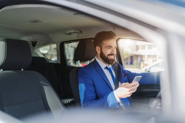 彼の車に座って 窓にもたれながらスマート フォンを使用して実業家の笑顔をクローズ アップ — ストック写真