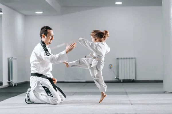 Sonriente Entrenador Taekwondo Caucásico Dobok Arrodillado Sosteniendo Mano Mientras Niña — Foto de Stock