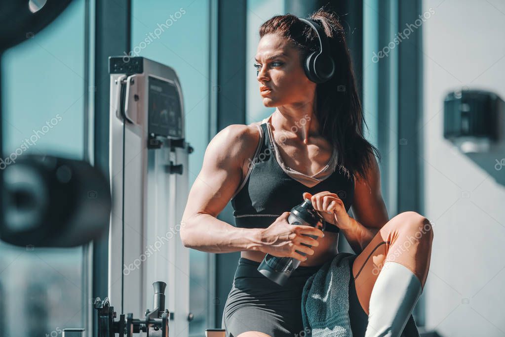 Joven en ropa deportiva y auriculares trabaja con pesas en el