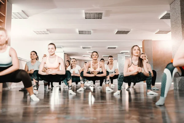 Leende Grupp Kaukasiska Kvinnor Gör Uthållighet Huk Position Gymmet Bakgrunds — Stockfoto
