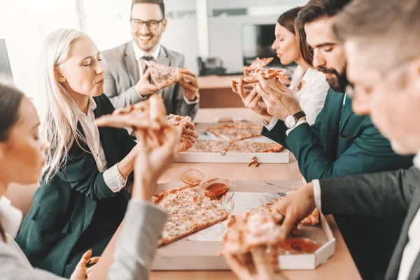 フォーマルウェアの幸せな同僚の小さなグループは 昼食のために一緒におしゃべりやピザを食べます チームでベストを尽くすのではなく チームにとってベストを尽くす — ストック写真