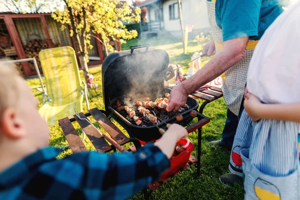 Familie Rond Grill Grillen Twirling Vlees Groenten Terwijl Staande Achtertuin — Stockfoto