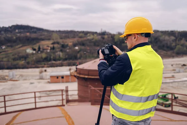 白人摄影师与黄色背心和头盔在建筑工地拍照 — 图库照片