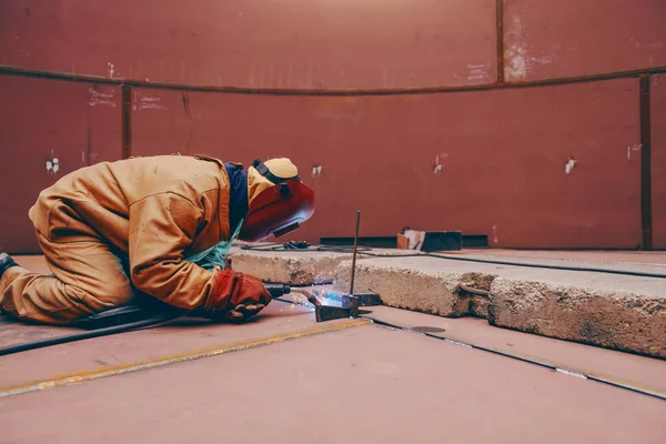 施工现场金属塔内身穿防护服 面罩蹲 焊接的工人 — 图库照片