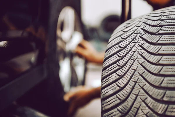 ワークショップでしゃがんでいる間に自動車整備士がタイヤを交換するのをクローズアップ タイヤの選択的焦点 — ストック写真