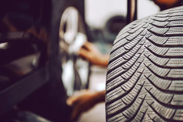 Fechar Auto Mecânico Trocando Pneu Enquanto Agacha Oficina Foco Seletivo — Fotografia de Stock