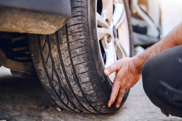 Primo Piano Del Meccanico Auto Cambiando Pneumatico Mentre Accovacciato Officina — Foto Stock