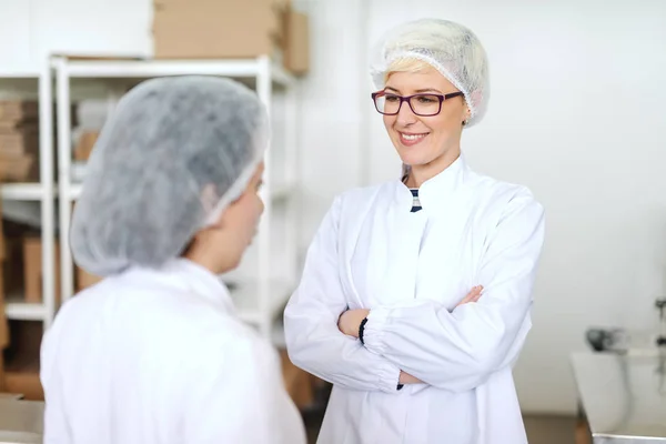 滅菌均一製品の品質について上司と話をし ホールディングの腕で金髪の白人従業員を渡った 食品工場の内部 — ストック写真