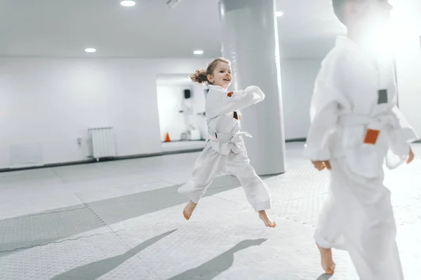 Hymyilevä Iloinen Valkoinen Pieni Tyttö Hyppää Taekwondo Koulutusta Yllään Dobok — kuvapankkivalokuva