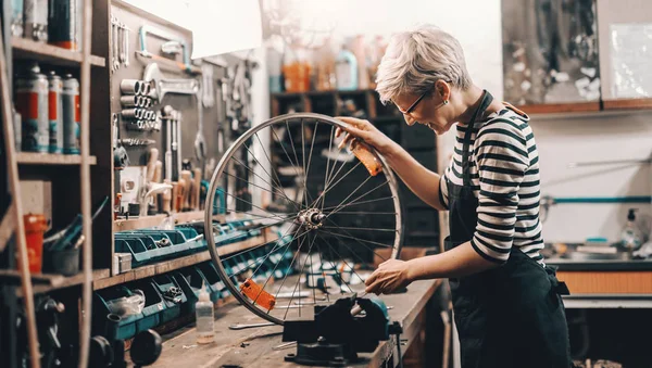 Schattig Kaukasische Vrouwelijke Werknemer Houden Fietswiel Terwijl Fiets Werkplaats Repareren — Stockfoto
