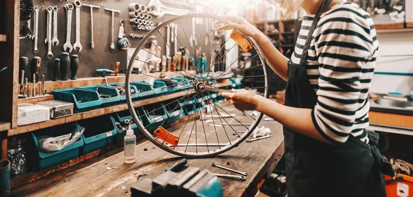 Schattige Vrouwelijke Werknemer Die Fiets Wiel Vasthoudt Repareert Terwijl Hij — Stockfoto