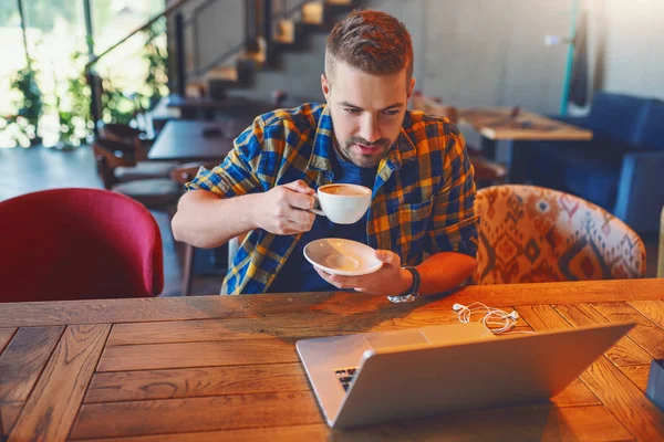 Joven Blogger Caucásico Camisa Cuadros Bebiendo Café Mirando Computadora Portátil — Foto de Stock