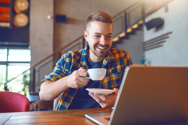 Joven Blogger Caucásico Camisa Cuadros Bebiendo Café Mirando Computadora Portátil — Foto de Stock