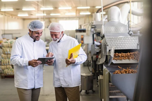 Dva Dělníci Uniformách Dívají Tabletu Zatímco Stojí Továrně Jídlo Starší — Stock fotografie