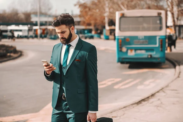 Pensive Bearded Businessman Turquoise Suit Holding Luggage Using Smart Phone Royalty Free Stock Images