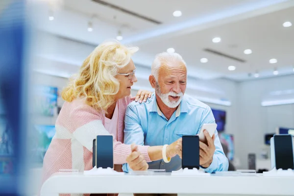 Linda Sonriente Pareja Ancianos Pie Tienda Tecnología Elección Nuevo Teléfono —  Fotos de Stock