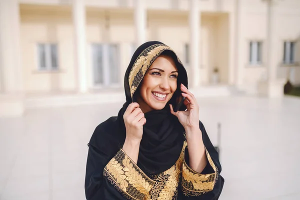 迷人的微笑穆斯林妇女穿着传统服装使用智能手机 而站在外面的肖像 — 图库照片