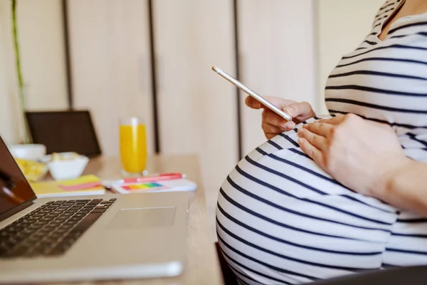 Молодая Беременная Женщина Использует Смартфон Сидя Столом Столе Ноутбук Стекло — стоковое фото