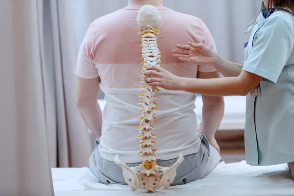 Enfermeira Caucasiana Segurando Modelo Coluna Vertebral Contra Costas Dos Pacientes — Fotografia de Stock