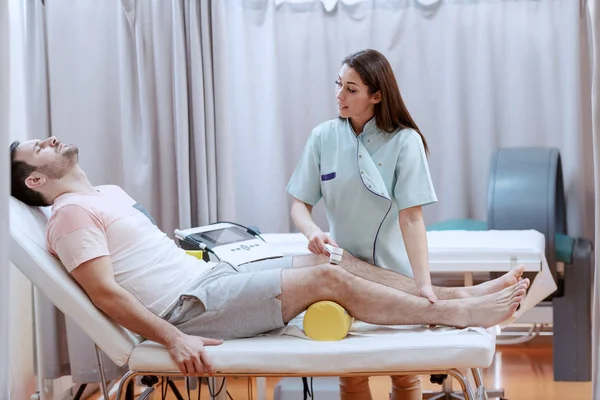 Young Caucasian Female Nurse Using Electrolysis Device Heal Patients Knee — 스톡 사진