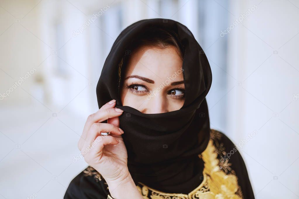 Encantadora mujer musulmana en ropa tradicional de pie frente a su casa y  tomar selfie.