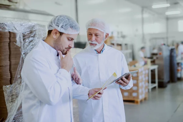 Zwei Mitarbeiter Der Qualitätskontrolle Sterilen Weißen Uniformen Beim Datenvergleich Älterer — Stockfoto