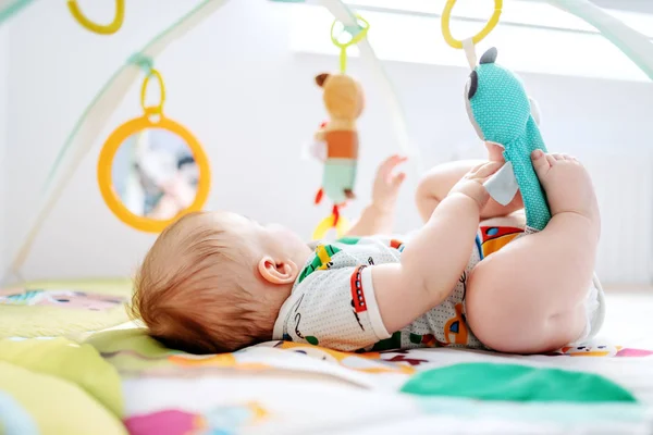可爱的六个月大的男孩躺在床上玩婴儿床玩具 健康成长理念 — 图库照片