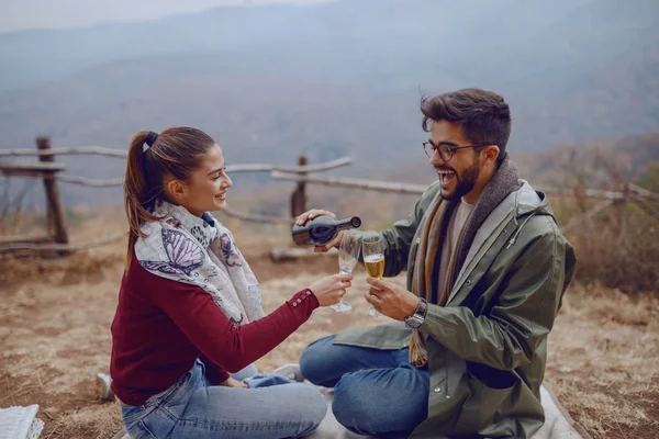 秋にピクニックを楽しむ愛のかわいいカップル多文化カップル 眼鏡にシャンパンを注ぐ男 — ストック写真