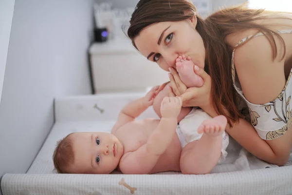 Šťastná Mladá Kavkazská Matka Líbá Dětské Nohy Zatímco Stojí Ložnici — Stock fotografie