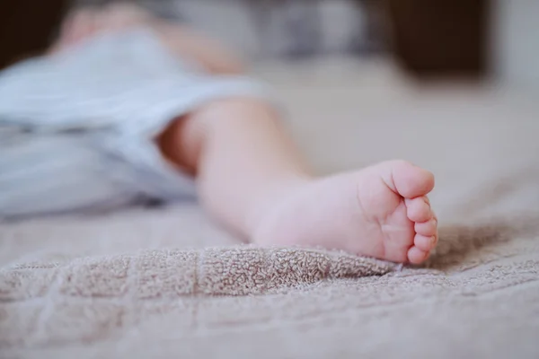 Avvicinamento di piccoli piedini. Concentrazione selettiva sulle dita. Bambino sdraiato sul letto . — Foto Stock