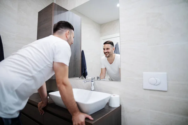 Pohledný Kavkazan Usmívá Pyžamu Moderní Koupelně Dívá Zrcadla Ranní Čas — Stock fotografie