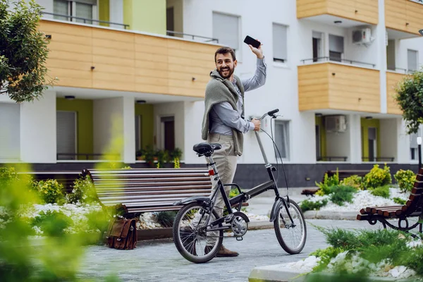 迷人的笑着友好的高加索商人 一边拿着自行车和智能手机一边走一边挥手 — 图库照片