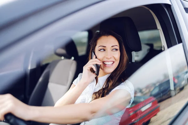 Atractiva Morena Caucásica Sonriente Conduciendo Coche Hablando Por Teléfono Mientras —  Fotos de Stock