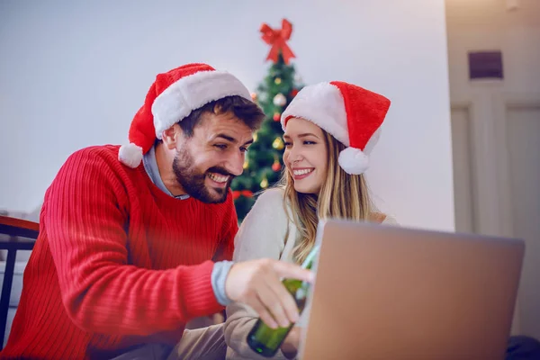 Happy Attractive Caucasian Couple Santa Hats Heads Sweaters Sitting Floor — ストック写真